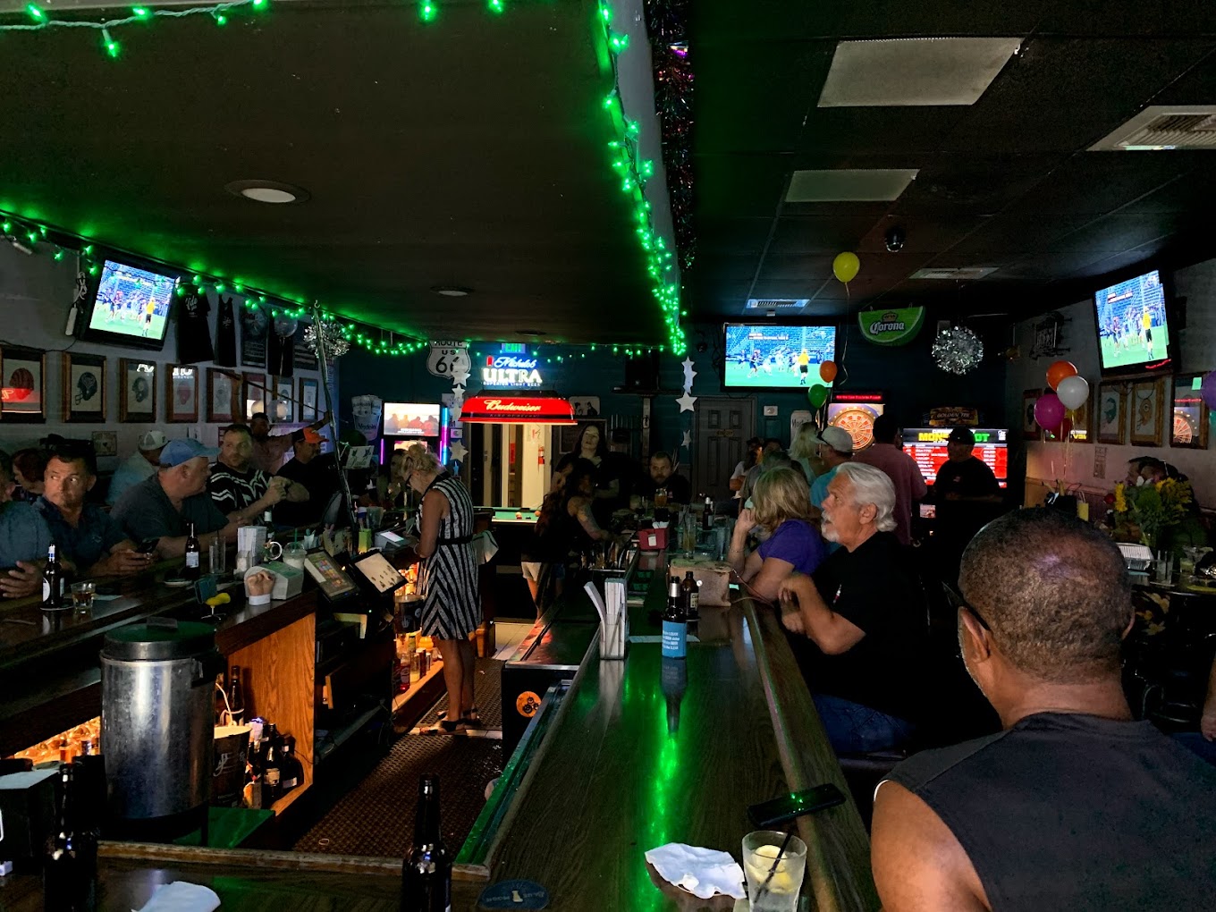 a full bar with people enjoying drinks and a game on tv