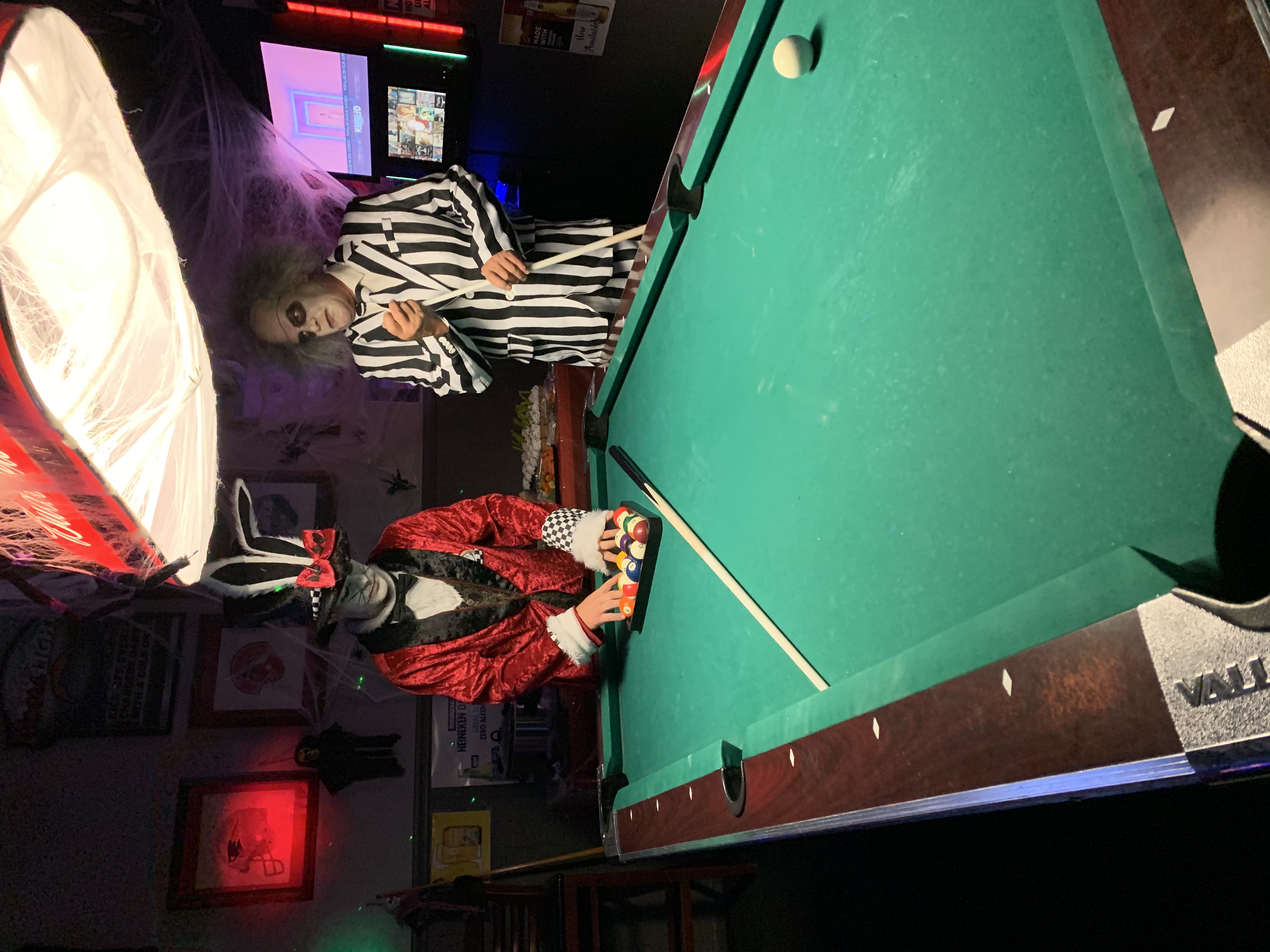 people in halloween costumes setting up a game of pool